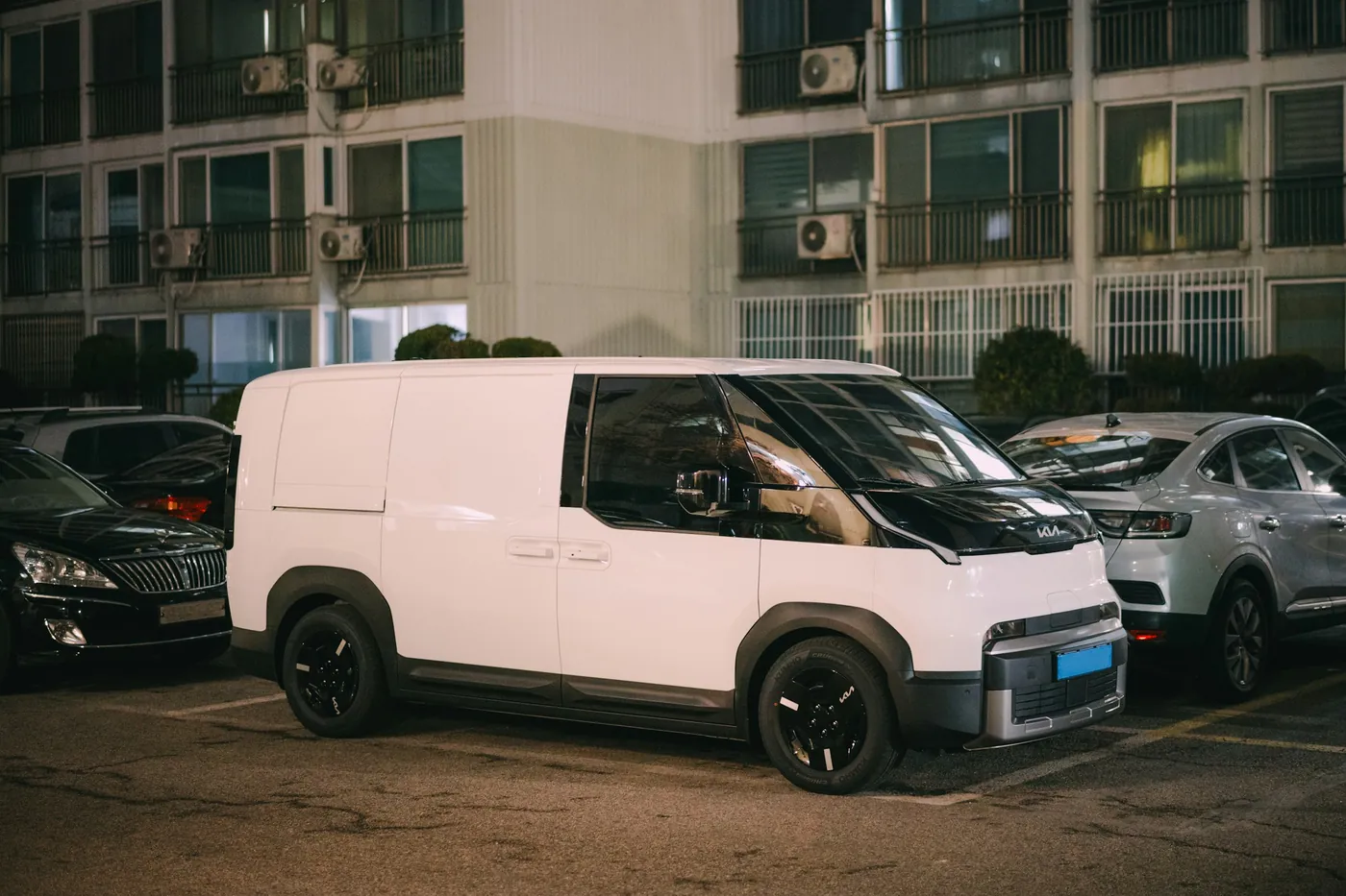 Ein weißer Transporter in der Abenddämmerung an einer Straße vor einem Wohnhaus