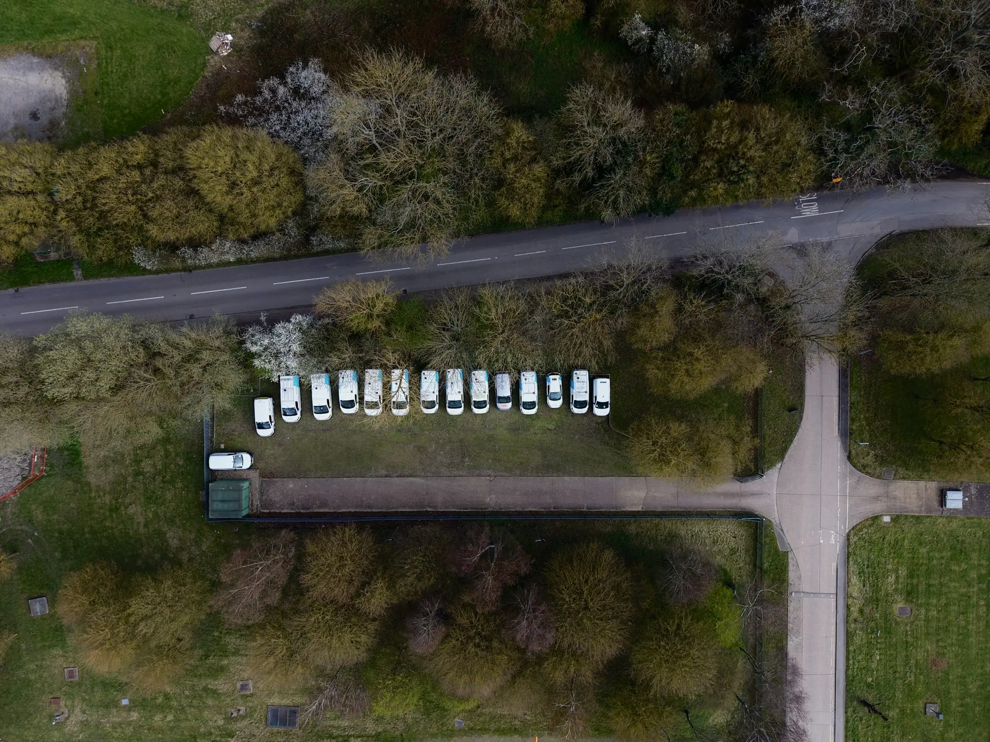 Luftaufnahme einer Flotte weißer Transporter, die entlang einer Straße parken